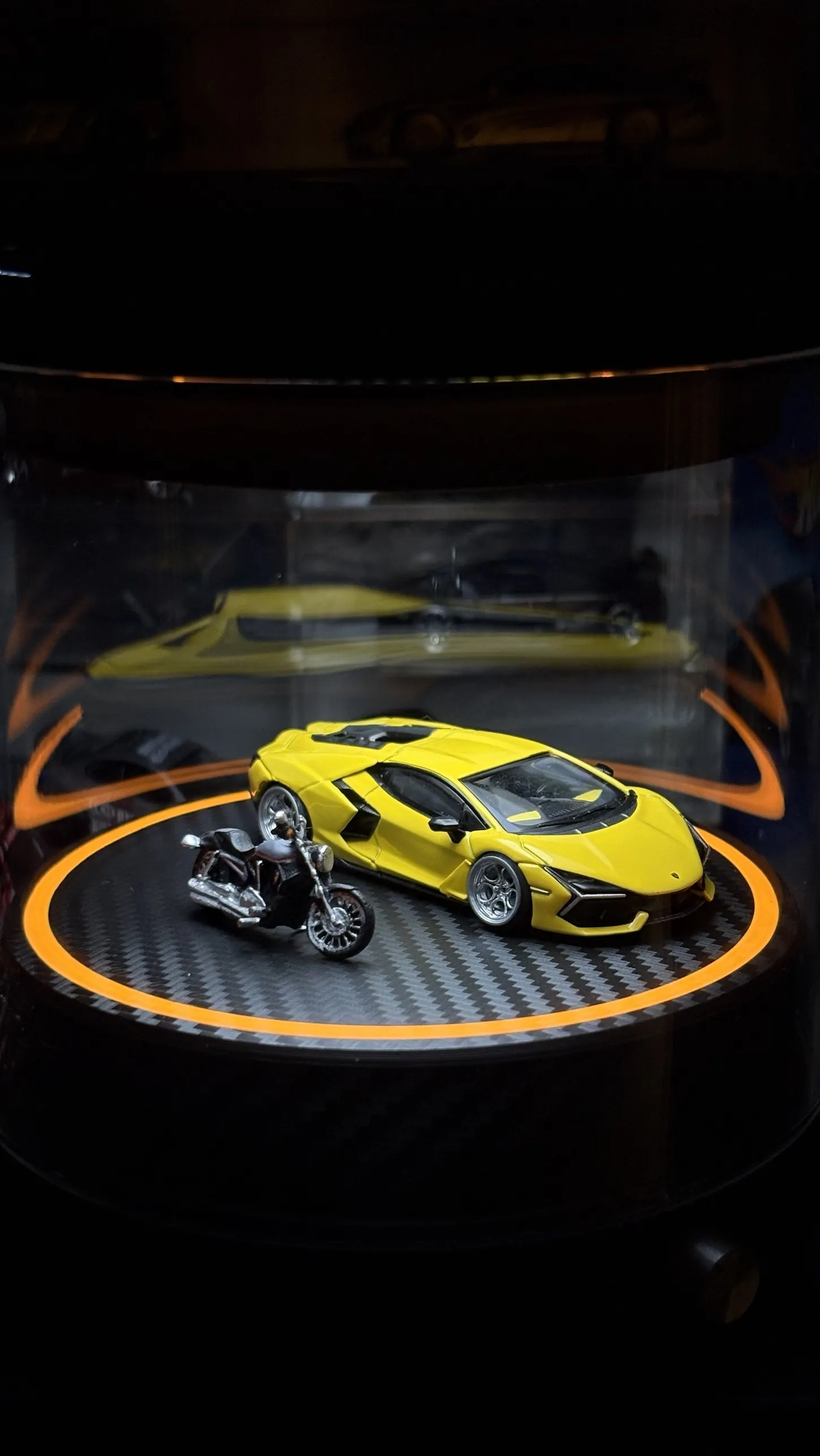 A yellow Lamborghini diecast model lit in a display case with an orange ring light